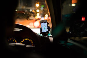 Interior of a cart at night with a smartphone mounted on the dash displaying Uber directions for the driver.