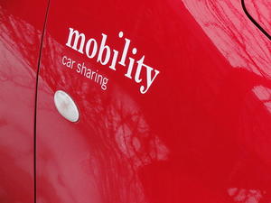 Close up image of "mobility car sharing" painted in white on a red car.